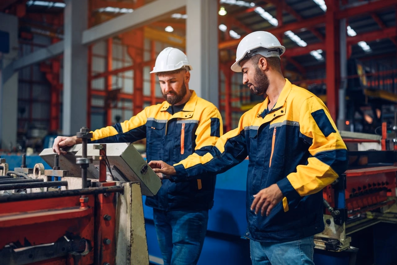 Two JGW Machine technicians reviewing electro-mechanical assembly controls on industrial manufacturing equipment